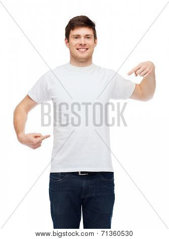 t-shirt design, gesture and people concept - smiling young man in blank white t-shirt pointing fingers on himself