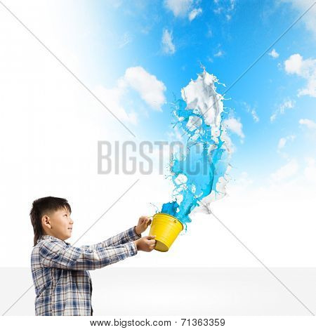 Young boy splashing colorful paint from bucket