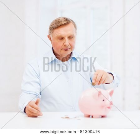 savings, oldness,business and banking concept - old man putting coin into big piggy bank