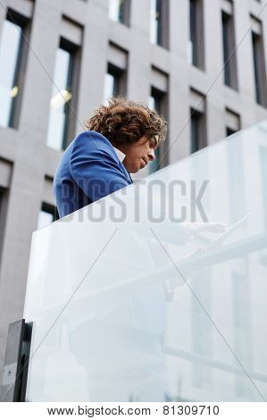 Shot of a mature businessman standing against office building using a digital tablet