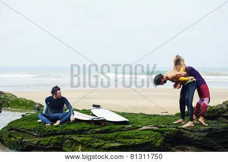 Young surfers having a good time waiting waves on beautiful surf spot standing against the ocean