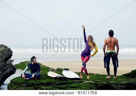 International group of friends having fun waiting big waves for surfing
