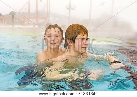 Brothers Are Swimming In The Outside Area Of A Thermic Pool In Wintertime