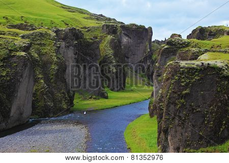 Iceland in the summer. Canyon Fjadrargljufur and cold fast river with a pebble bottom
