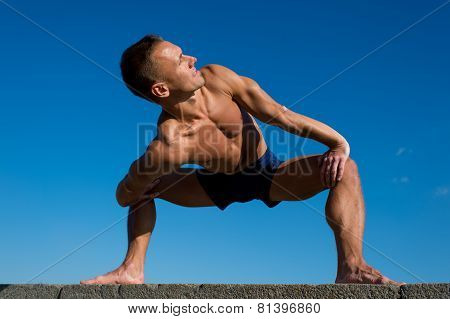 Happy Athletic Man Doing Yoga Asanas In The Park At Sunny Day