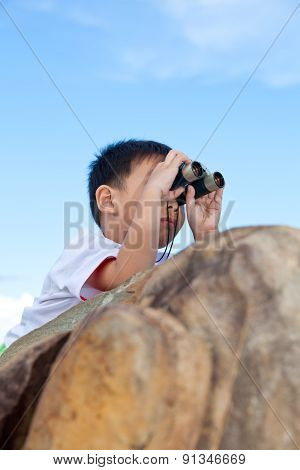 Happy Little Boy Exploring Outdoors Clambering On A Rock With Telescope
