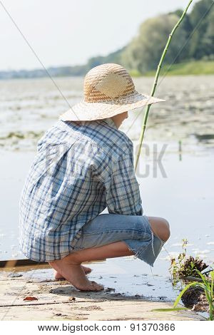 Sitting on wooden bridge shoeless fisherman with fishing rod