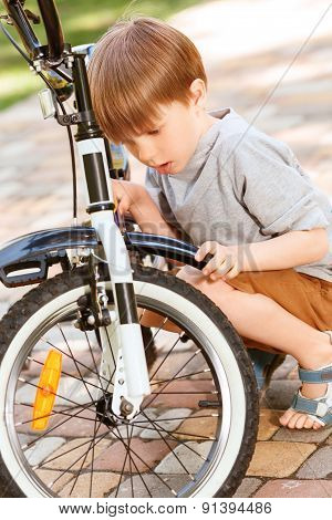 Close up of little boy repairing his bike
