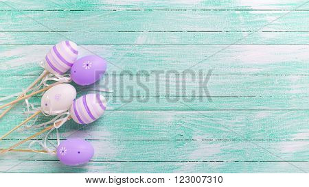Easter/spring background. Decorative violet eggs on turquoise wooden background. Selective focus. Place for text.