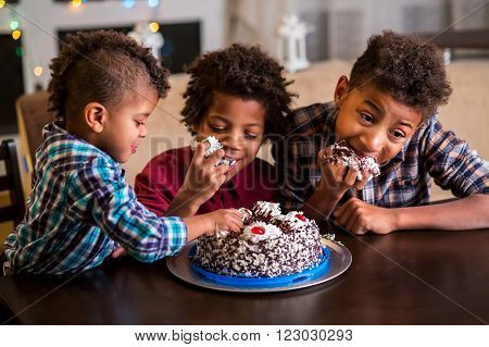Three afro boys eating cake. Three black kids eat cake. Time for dessert. They waited for so long.