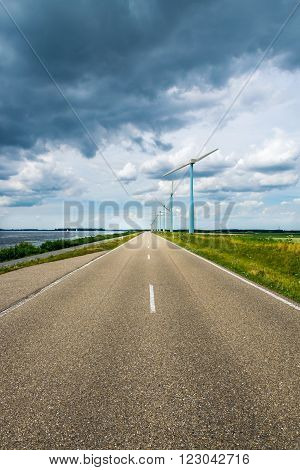 Dutch road with windmills, lake and impressive clouds