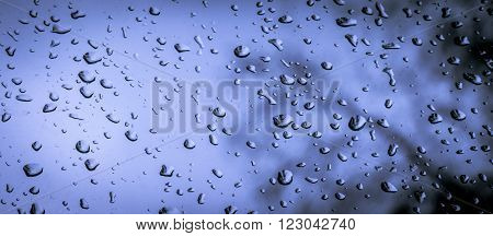 raindrops against a cold and dark sky on a window