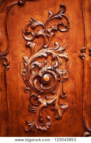 Beautiful ornately carved wooden pattern on a dark background on an antique door.