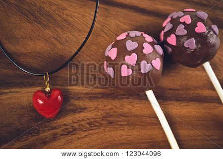 Cakepops and red heart decoration on a wooden background