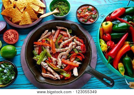 chicken fajitas in a pan with sauces chili and sides Mexican food