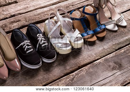 Female shoes on old floor. Tankette shoes and fabric keds. Footwear for every taste. From simplicity to luxury.