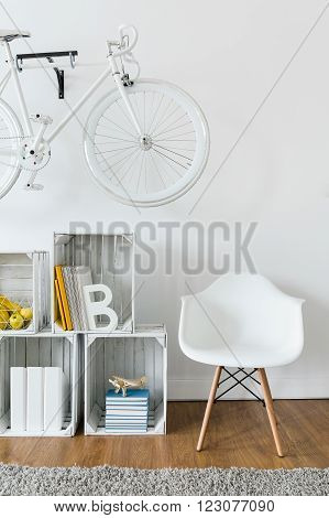 Close-up of cozy reading corner with wooden shelf and white armchair in modern lounge