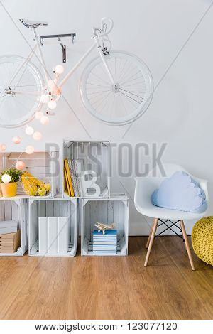 Bright space in student's flat. Wooden floor and white wall with bicycle on it