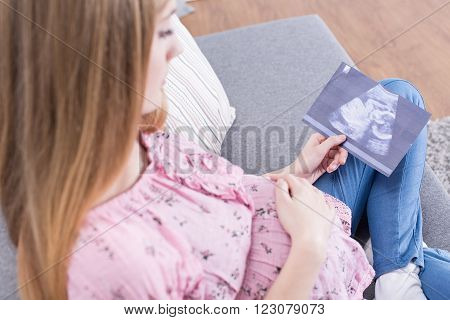Pregnant teenage girl looking at usg photo of her baby