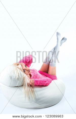 Portrait of a sexy young woman sitting on pouf in studio background.