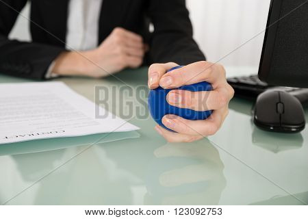 Close-up Of Businesswoman Pressing Stressball In Office