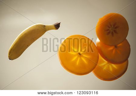 slices of persimmon and banana against the sky