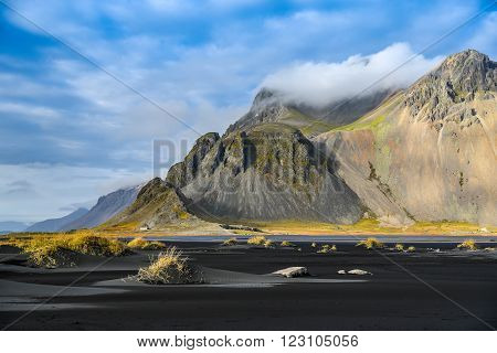 Mountains and black volcanic lava sand dunes by the sea in winter of Stokksness Iceland