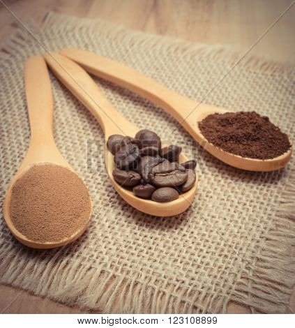 Coffee beans ground coffee and instant coffee on wooden spoon lying on jute burlap