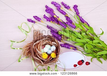 Easter. Nest with eggs and chickens on wooden background with lilac flowers with a sign for the label