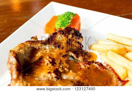 traditional style juicy porkchop with french fried on white plate in restaurant for lunch