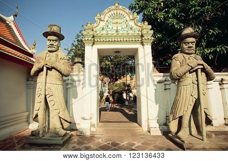 BANGKOK, THAILAND - FEB 14: Sculptures of Farang guards at entrance of historical monastery Wat Pho on February 14, 2015. Wat Pho is a Buddhist temple complex founded in 16th century