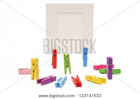 Three clothespins standing others are semicircular. Two clothespins holding white frame behind the