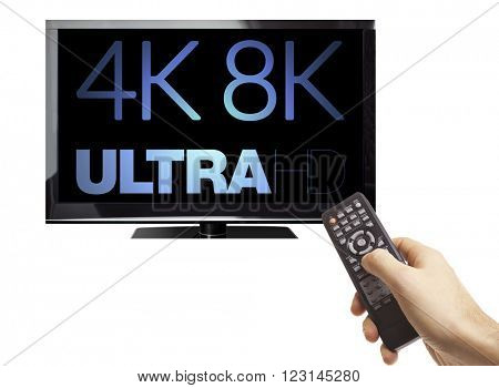Male hand holding remote control of a TV with 8K 4320p Ultra HD technology logo on