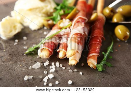 Bread sticks grissini with prosciutto ham and mozzarella cheese, close up