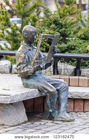 ZAKOPANE POLAND - MARCH 09 2016: Highlander sitting on a rock and reading a newspaper made of bronze figure created to commemorate the 20th anniversary of the magazine Tygodnik Podhalanski
