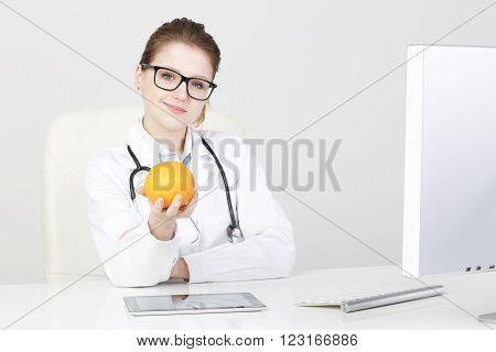 young beautiful female dietitian holding a healthy orange.