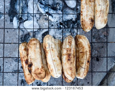 Grilled bananas on a steel mesh with firewood