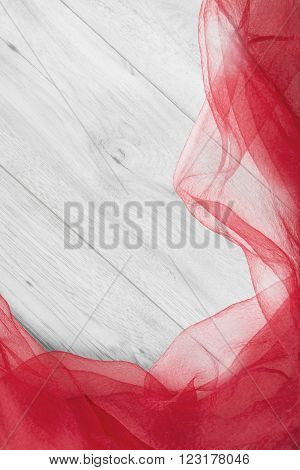 Crumpled red silk over white wooden background