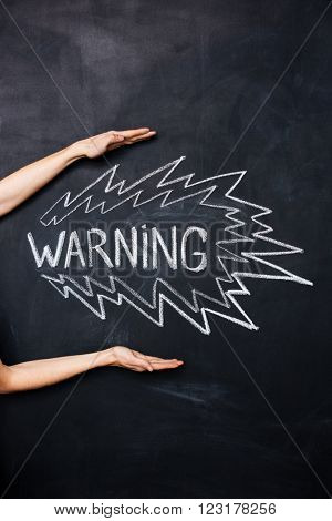 Two hands showing warning drawn on blackboard by chalk