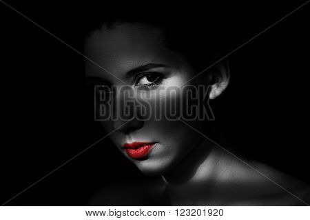 Artistic beauty portrait of young woman with creative lighting effect. Fashion close up black and white photo of girl face with red lips in low key.