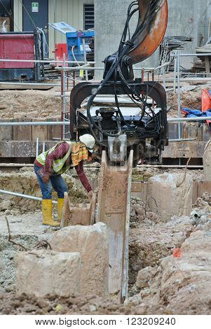 SELANGOR, MALAYSIA - MARCH 12, 2015: Sheet pile cofferdam driven machine at the construction site. This machine drove the sheet pile to the earth using vibrated hydraulic arm. Workers control.