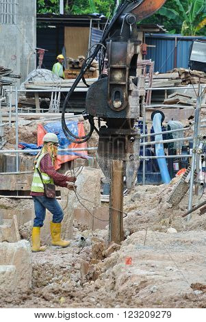 SELANGOR, MALAYSIA - MARCH 12, 2015: Sheet pile cofferdam driven machine at the construction site. This machine drove the sheet pile to the earth using vibrated hydraulic arm. Workers control.