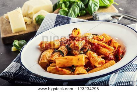 Italian and Mediterranean cuisine. Pasta Rigatoni with tomato sauce basil leaves garlic and Parmesan cheese. An old home kitchen with old kitchen utensils.
** Note: Shallow depth of field