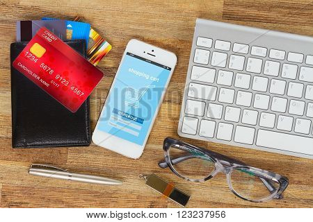 desktop with internet store page on mobile  phone and wallet with plastic cards