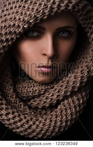 Portrait of a young girl in a scarf-snood large knitting on a black background