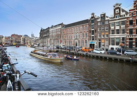 AMSTERDAM, THE NETHERLANDS - AUGUST 19, 2015: View on Rokin from bridge Doelensluis. Street life, Canal, tourists, bicycle and boat in Amsterdam. Amsterdam is capital of the Netherlands on August 19, 2015.