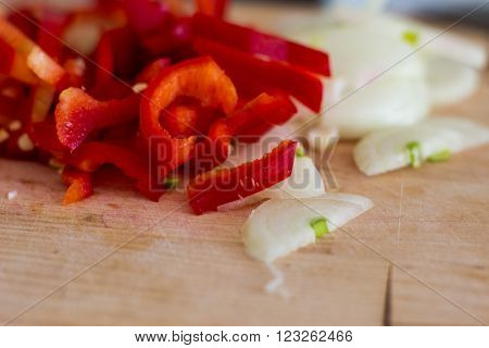 Chopped onion and pepper on a wooden board close up