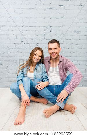 Two Cheerful Lovers Sitting Barefoot On The Floor And Huging