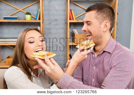 Portrait Of Happy Couple In Love Feeding Each Other With Pizza