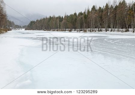 Irkutsk Region, Russia -March,20 2016: Icebound river on a cloudy spring day in the village. Kochergat Irkutsk Region Russia